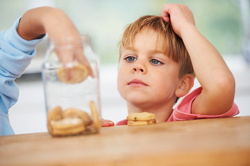 Image showing Cute, cookies jar and boy kid by the kitchen counter eating a sweet snack or treat at home. Smile, dessert and hungry young child enjoying biscuits by a wooden table in a modern family house.