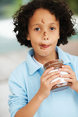 Image showing Cute, portrait and child with chocolate spread at a home with delicious, sweet snack or treat. Smile, happy and face of young boy kid from Mexico eating nutella jar licking lips at modern house.