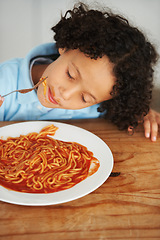 Image showing Hungry, food and child eating spaghetti by the wooden kitchen counter for lunch at home. Pasta, tomato and boy kid enjoying a meal for dinner or supper for nutrition at a table in a modern house.