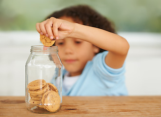 Image showing Craving, cookie jar and boy child by the kitchen counter eating a sweet snack or treat at home. Smile, dessert and cute hungry young kid enjoying biscuits by a wooden table in a modern family house.