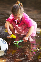 Image showing Girl, child and play with toys in mud for freedom, activity and muddy fun in sunshine weather or outdoor. Kid, female and river of person with peace for playing, enjoyment and relax in dirt water