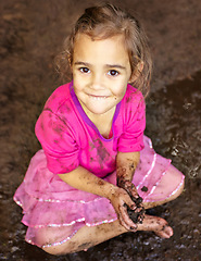 Image showing Girl, kid and portrait with smile in mud for freedom, playing and muddy fun in sunshine weather or outdoor. Child, female and face of person with happiness for activity, enjoyment and relax in dirt