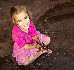 Image showing Girl, child and portrait with happiness in mud for freedom, playing and muddy fun in sunshine weather or outdoor. Kid, female and face of person with smile for activity, enjoyment and relax in dirt