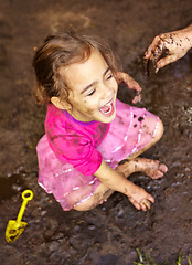 Image showing Girl, child and fun with laugh in mud for freedom, playing and muddy in sunshine weather or outdoor. Kid, female person and face with happiness for activity, enjoyment and relax with toy in cirt