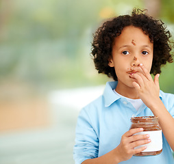 Image showing Cute, portrait and kid with chocolate spread at a home with delicious, sweet snack or treat. Smile, happy and face of young boy child from Mexico eating nutella jar licking lips at modern house.