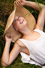 Image showing Hat, woman and relax on grass or lawn with happiness and freedom in summer. Outdoor, fashion and girl lying on lawn with a smile on face for holiday, vacation or free time in nature with wellness