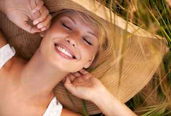 Image showing Woman, hat and relax on grass with peace, happiness and freedom in summer. Outdoor, fashion and girl lying on lawn with a smile on face for holiday, vacation or free time in nature with carefree joy