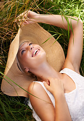 Image showing Summer, hat and woman relax on grass with happiness and freedom in nature. Outdoor, fashion and girl lying on lawn with a smile on face for holiday, vacation or free time in meadow with wellness