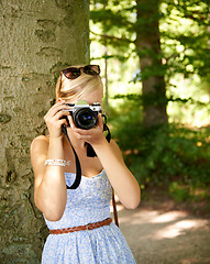 Image showing Camera lens, nature and photographer with woman in forest for relax, memory and travel photography. Summer, trees and adventure with female person for vacation, holiday and environmental tourism