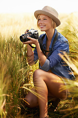 Image showing Woman smile, camera and photography with travel, vacation and holiday with wheat field and plants. Nature, photographer and outdoor with blog and countryside with photo for adventure and journey