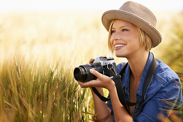 Image showing Field, smile and woman with a camera, photographer and sunshine with tourism, travelling and nature. Person, photography or girl with summer, thinking or countryside with picture, freedom or creative