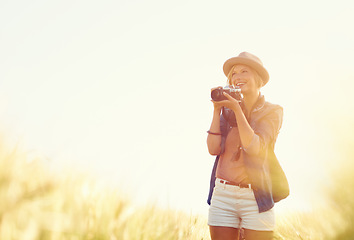 Image showing Outdoor, sunshine and woman with a camera, photographer and travelling with happiness, lens flare and adventure. Trip, photography or girl with nature, field or summer with vacation, picture or smile