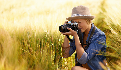 Image showing Woman, camera and photography in grass with travel, vacation and holiday with wheat field and plants. Nature, photographer and outdoor with blog and countryside with photo for adventure and journey