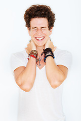 Image showing Smile, fashion and an edgy young male model in studio isolated on white background for rocker style. Accessories, eyes closed and a funky punk man in a casual clothes outfit for individual expression