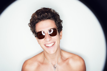 Image showing Man, sunglasses and smile in studio with spotlight, fashion or shirtless with edgy punk style by background. Person, fashion and happy by halo for confidence, attitude or jewelry for trendy aesthetic