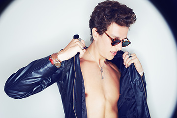 Image showing Man, sunglasses and leather jacket in studio with spotlight, fashion or thinking with punk style by background. Rockstar, fashion and halo with confidence, attitude or jewelry for trendy aesthetic
