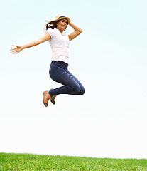 Image showing Nature, happy and woman jumping on grass for positive, joyful and confident attitude by blue sky. Smile, portrait and young female person from Canada leap on green lawn at outdoor garden in summer.