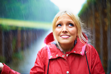 Image showing Woman, smile and raincoat for rain in nature, wet and cold from weather, winter and outdoor. Happy female person, fashion and red jacket is cool, rainfall and protection from water, face and vacation
