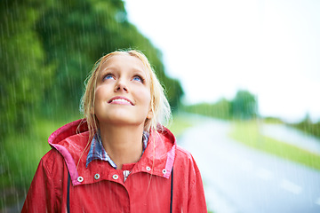 Image showing Woman, smile and raincoat in outdoor rainfall, wet and cold from weather, winter and nature. Happy female person, fashion and red jacket is cool, rain and looking up to sky by water, face and holiday