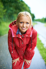 Image showing Smile, portrait and young woman in the rain with coat in nature, road or street for winter. Happy, positive attitude and female person from Australia in drizzle or storm weather in outdoor forest.