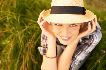 Image showing Portrait, hat and young woman in nature with a straw accessory sitting in an outdoor garden for fresh air. Happy, fashion and female person from Australia in forest, woods or field with casual style.