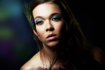 Image showing Portrait, makeup and peacock feather with a woman in studio on dark background for natural skincare or wellness. Face, skin or beauty and a confident young model looking creative with cosmetics