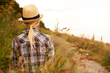 Image showing Woman, walk and relax in field or nature, peace and back in outdoors, meadow and flowers or plants. Female person, hike and trekking for fitness, exercise and health or wellness, grass and vacation