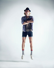 Image showing Portrait, jumping and man with fashion, retro and streetwear with confident guy isolated on a white studio background. Person, model and hipster with casual outfit, trendy clothes and floating in air