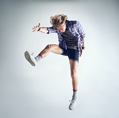 Image showing Man, hipster and fashion jump in studio dancing isolated, grey background or mockup space. Male person, glasses and funky socks or leap crazy energy or fun cool style, comedy or activity expression