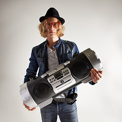 Image showing Boombox, fashion and portrait of a man in studio with music, radio or audio sound. Serious model person on grey background with denim outfit, glasses and hipster hat or retro style to listen to song