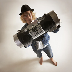 Image showing Boombox, portrait and fashion of a man in studio with music, radio or audio sound and above. Serious model person on a grey background with denim outfit, glasses and hipster hat to listen to song