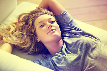 Image showing Portrait, relax and a woman on a sofa in the living room of her home on the weekend with a lighting filter. Peace, wellness and a happy young teen girl lying alone in her apartment for morning rest