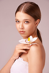 Image showing Woman, portrait or orchid beauty in studio for makeup look, cosmetic on pink background. Female person, model or face or floral flower bloom on shoulder elegant transformation, self care as mockup