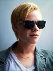 Image showing Portrait, sunglasses and a cool young boy in studio on a gray background for trendy youth style. Fashion, face and attitude with a confident person in shades to model an outfit as a teenage model