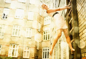 Image showing Portrait, smile and a woman on a ladder in an old city with flare for travel, freedom or adventure as a tourist. Building, energy and urban space with a happy young person in an city on bokeh