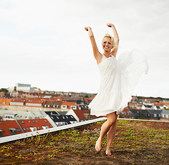 Image showing Woman, happiness and dancing on rooftop, carefree and outdoor with freedom, smiling and city. Wind, dancer and urban area for break, summer and smile on trip, barefoot and amsterdam spring time