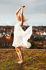 Image showing Woman, happiness and dancing on vacation, summer and outdoor for holiday, smiling and city. Wind, dancer and urban area for break, getaway and carefree on trip, barefoot and amsterdam spring time