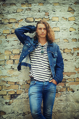 Image showing Man, portrait and fashion, streetwear and denim clothes with hair and relax against wall background. Urban, young and gen z with serious model outdoor, casual outfit and hipster, cool and trendy