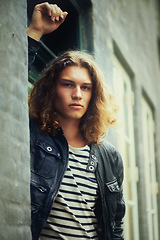 Image showing Portrait, fashion and a man on a wall in the city during summer for travel or tourism in the afternoon. Street, cool and confident young model leaning on a building in an urban town for trendy style