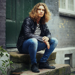 Image showing Man, fashion and portrait or leather jacket rebel or trendy style, clothes or denim jeans. Male person, model and face sitting outdoor step for edgy look or cool confidence, rocker or doorway brick