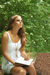 Image showing Park, thinking and a woman writing in a journal outdoor during summer for mental health or expression. Creative, diary and peace with a young person in a green garden to relax for wellness or freedom