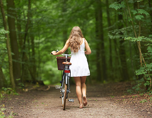 Image showing Back, bike and a woman walking in the forest for travel, freedom or adventure in nature during spring. Sustainability, relax and a person pushing her bicycle in the countryside for peace or quiet