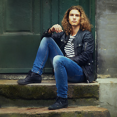 Image showing Man, fashion or portrait or leather jacket style rebel or trendy, clothes or denim jeans. Male person, punk streetwear or face sitting doorway step for edgy look or cool confidence, rocker or unique