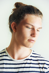 Image showing Young, man and thinking with face in studio for looking, idea or vision on white background in London. Male model, pose and hairstyle with bun, different and indie for clothes, fashion and trendy