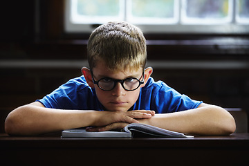 Image showing Kid, school and angry on desk, book and staring for education, adhd and child development. Anxiety, stress and burnout from dyslexia, moody or mental health issue for studying, frustrated and autism