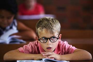 Image showing Classroom, student and boy with thinking, bored and education with glasses, learning and teaching. Kid, school and child with eyewear, development, notebook or tired with a test, morning and studying