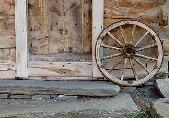 Image showing A wooden wheel leaning against a wall