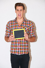 Image showing Screaming, angry and man with blackboard for education in studio isolated on white background for mockup, advertising or marketing. Blank chalkboard, space and frustrated person with stress at school