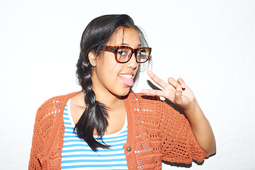 Image showing Fashion, peace sign and portrait of woman with tongue out on white background with style, confidence and emoji. Hipster, hand gesture and person in trendy clothes, casual outfit and glasses in studio