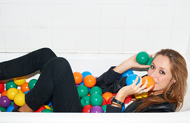 Image showing Portrait, balls and woman in bathtub for fashion, style and trendy hipster at home. Happy person in tub with color, party or plastic with body in bathroom, relax in edgy and cool clothes in Canada